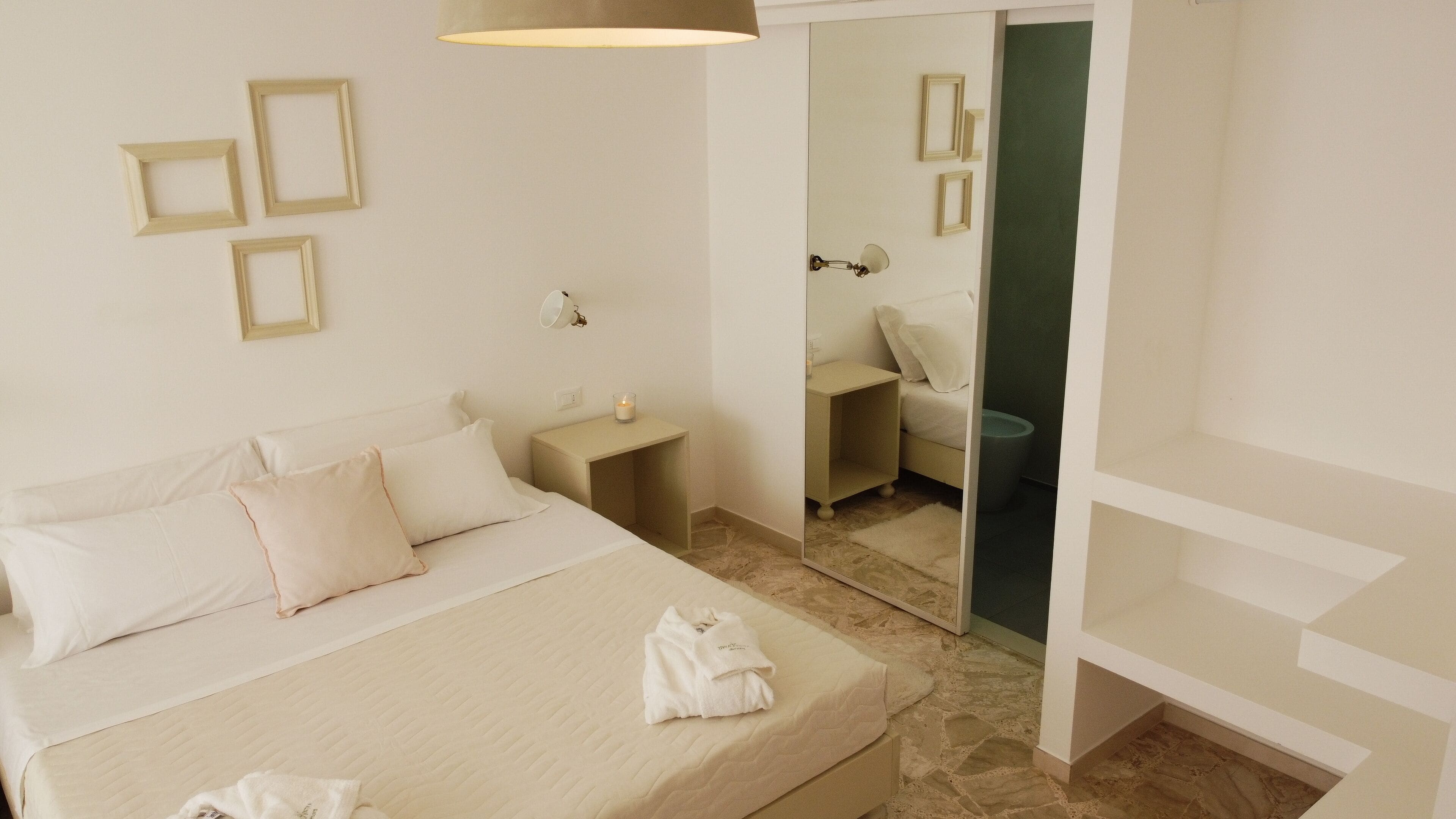 Une chambre d’hôtel comprenant un lit, une table de chevet, un miroir et une petite salle de bain.
