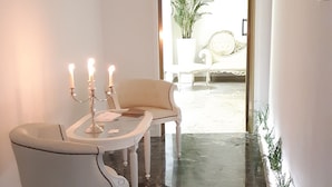 A hallway with a marble floor, a white chair, a table with a candelabra, and a potted plant. - Dimora TerraNostra & Spa (Ugento)