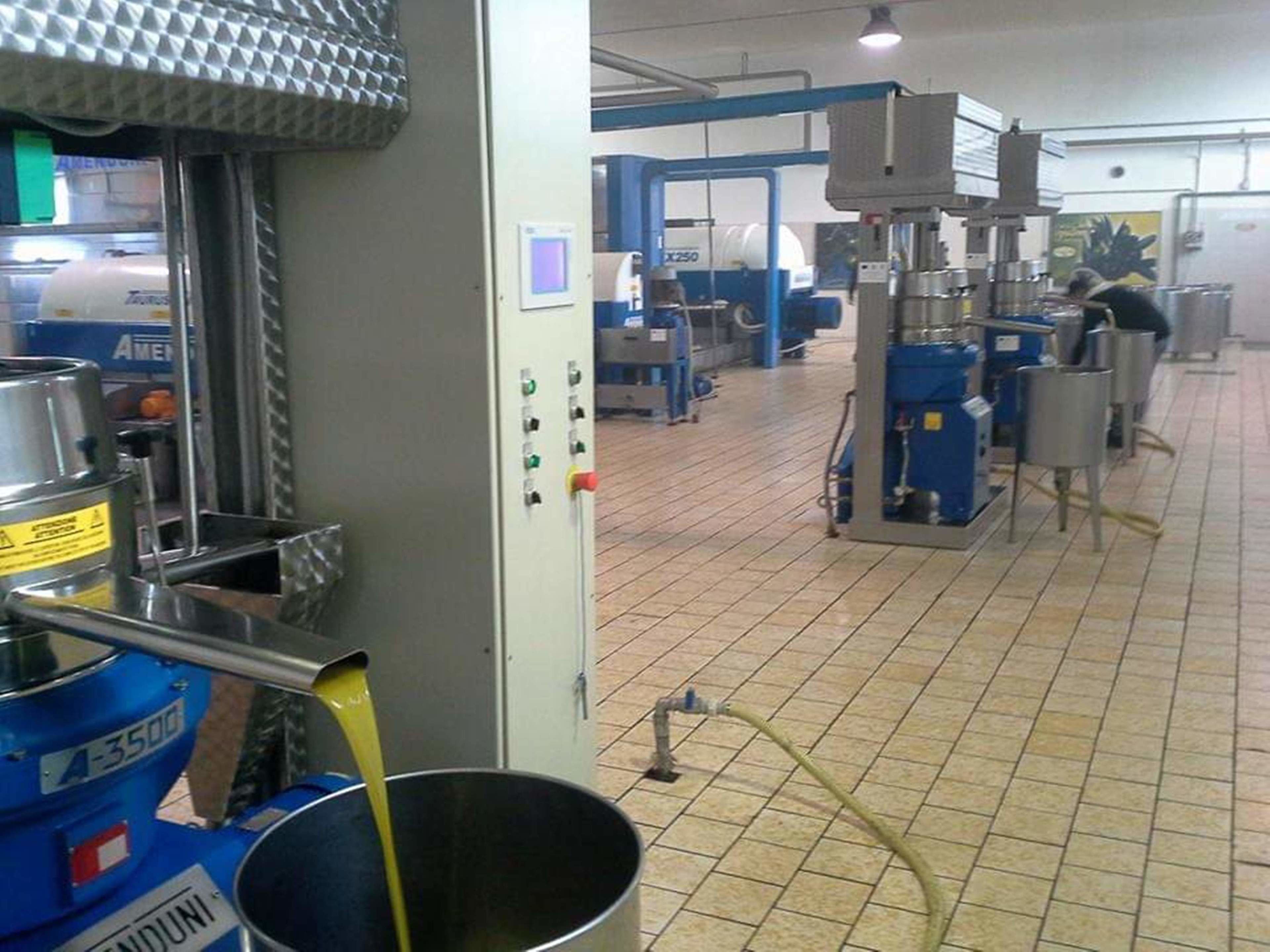 Una zona de cocina con equipamiento industrial, una máquina mezcladora grande y un recipiente metálico.
