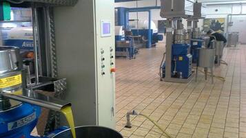 Una zona de cocina con equipamiento industrial, una máquina mezcladora grande y un recipiente metálico.