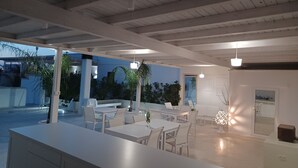 An open-plan dining area with white furniture and a view of the outdoors. - Dimora TerraNostra & Spa (Ugento)