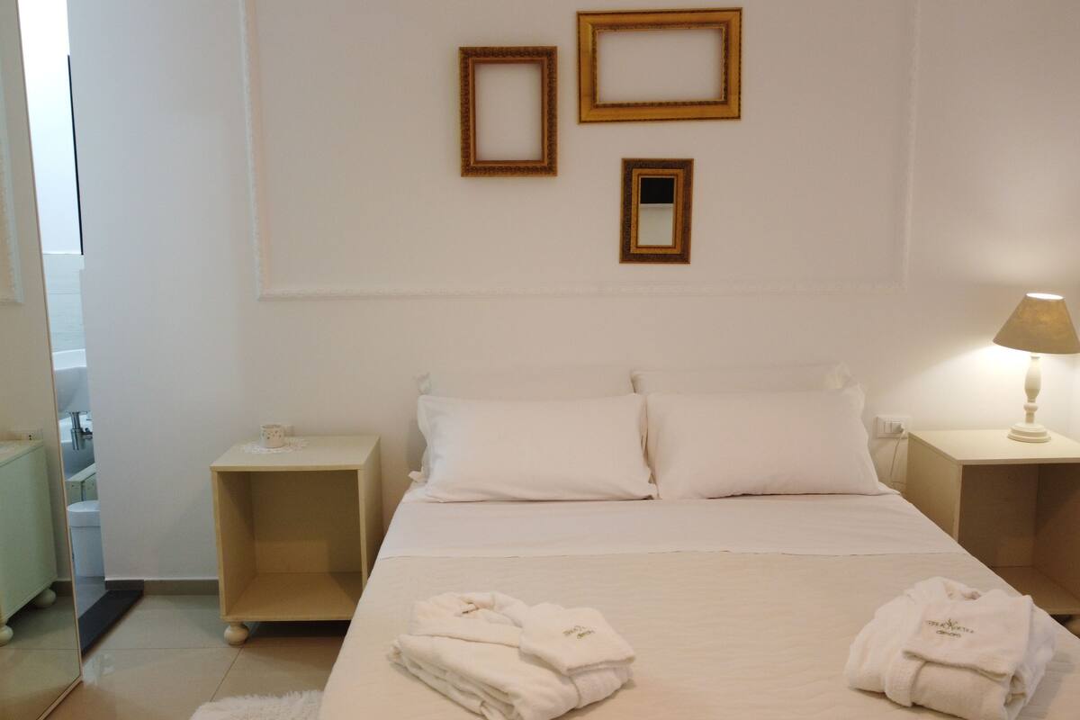 A hotel room with a bed, two bedside tables, a lamp, and towels.