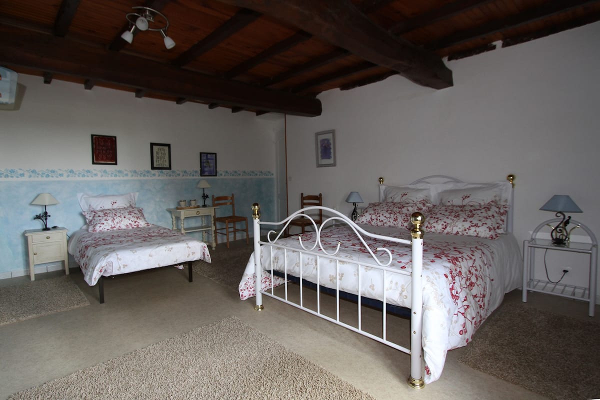 A bedroom with two beds, wooden headboard, a desk, and a chair.