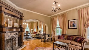 Amplia sala de estar con chimenea, un sofá, una mesa de centro y un comedor con candelabro.