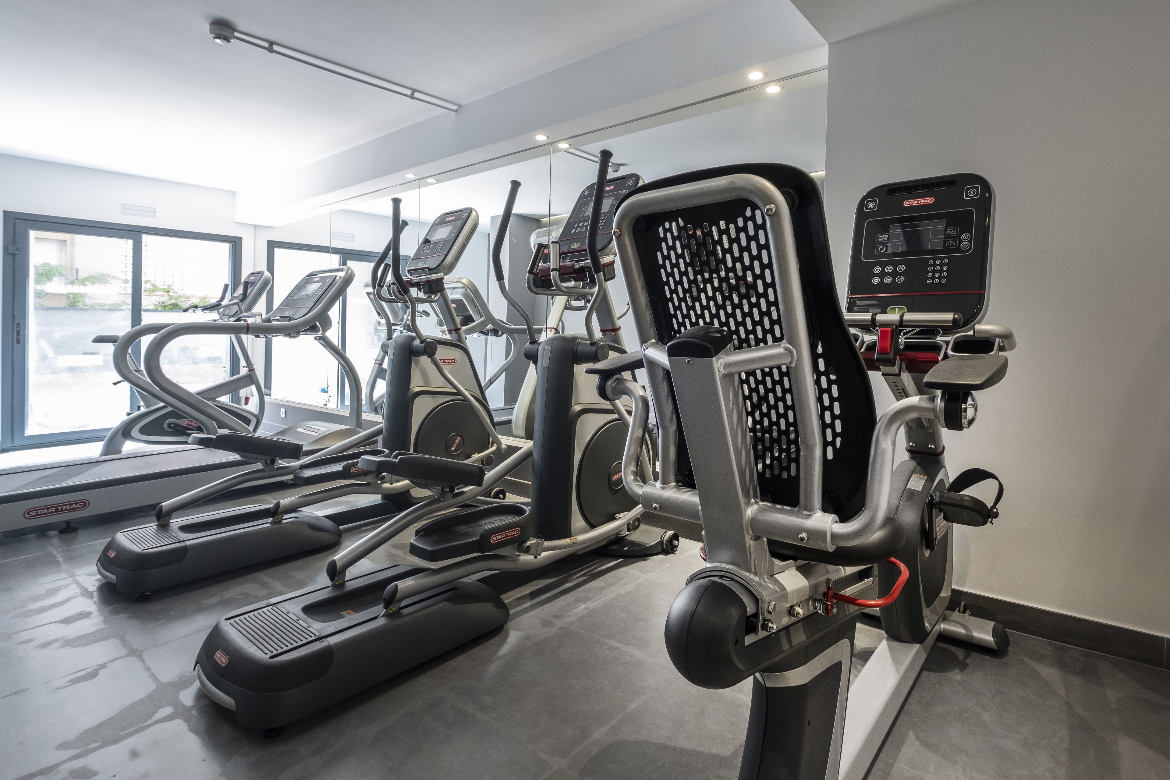 Una palestra con diverse macchine per esercizi, tra cui tapis roulant ed ellittiche.