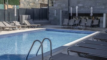 Una piscina cubierta, una piscina al aire libre, sombrillas, tumbonas
