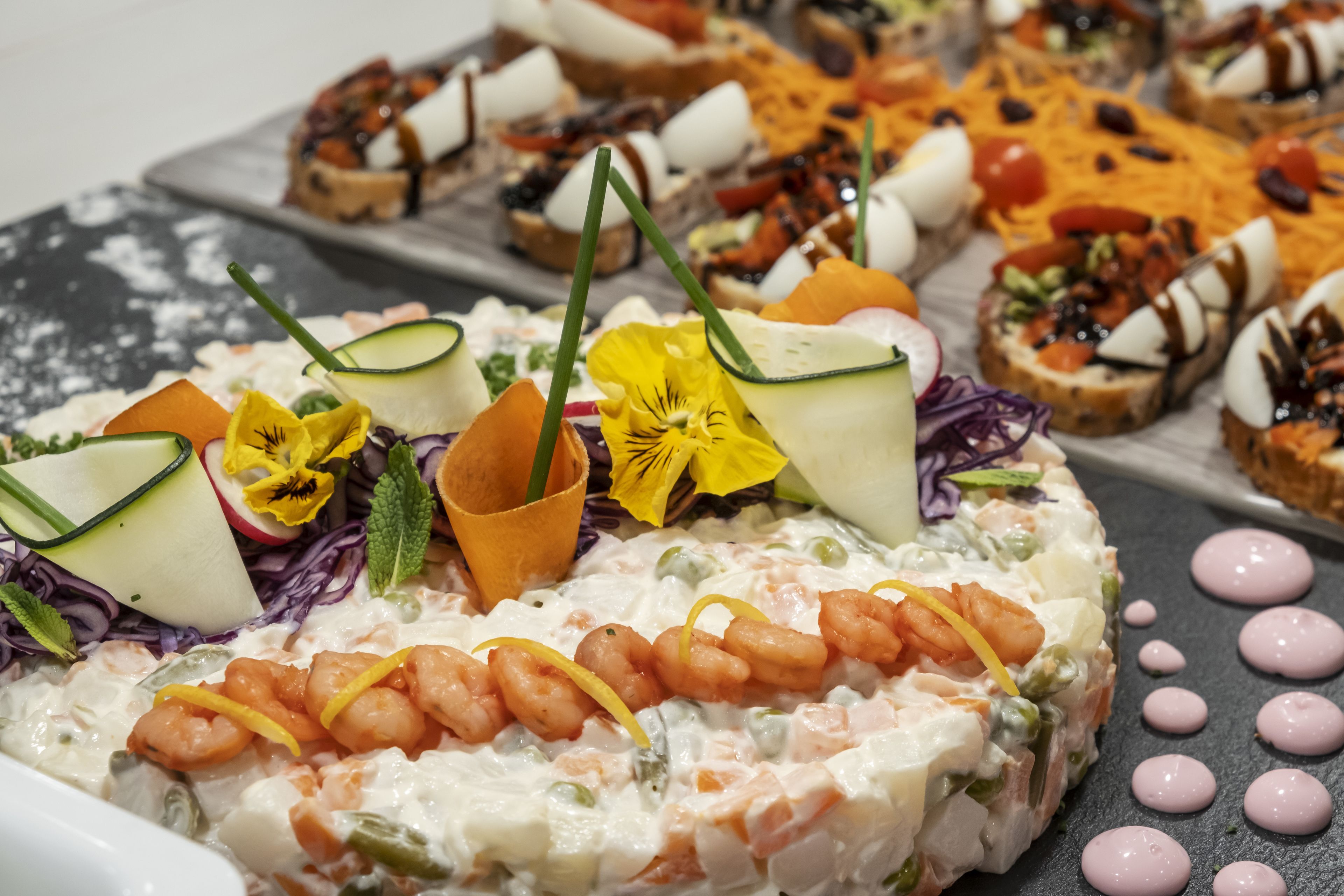 A variety of appetizers including shrimp salad, vegetable slices, and a fruit salad with a decorative drink.