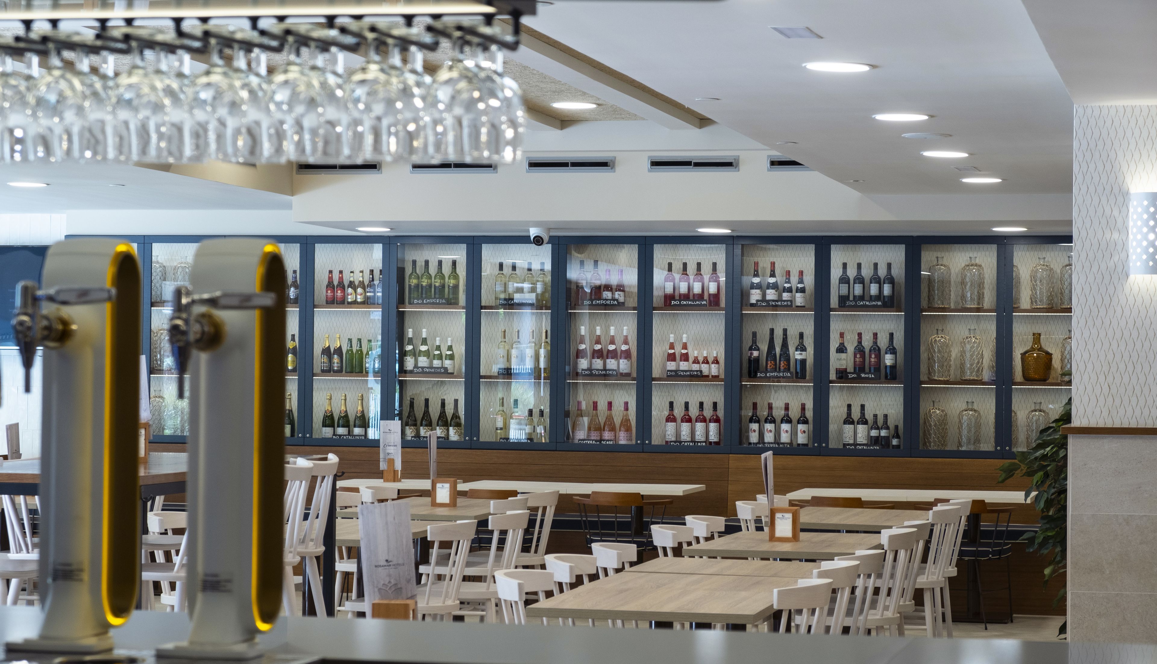 A restaurant with a wine display, tables, and chairs.