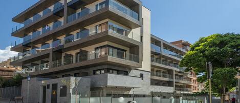 Un hôtel à plusieurs étages doté de balcons, d’un panneau indiquant un parking et surplombant un ciel dégagé.