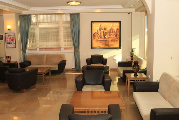 A hotel lobby with a sofa, chairs, a coffee table, and a painting on the wall. - Evkuran Otel (Ankara)