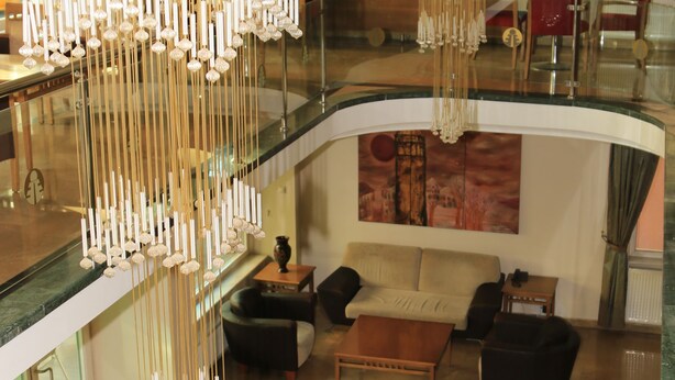 Eine großzügige Lobby mit hoher Decke, einer gemütlichen Sitzecke mit Sofas und einem Couchtisch sowie einem modernen Kronleuchter.
