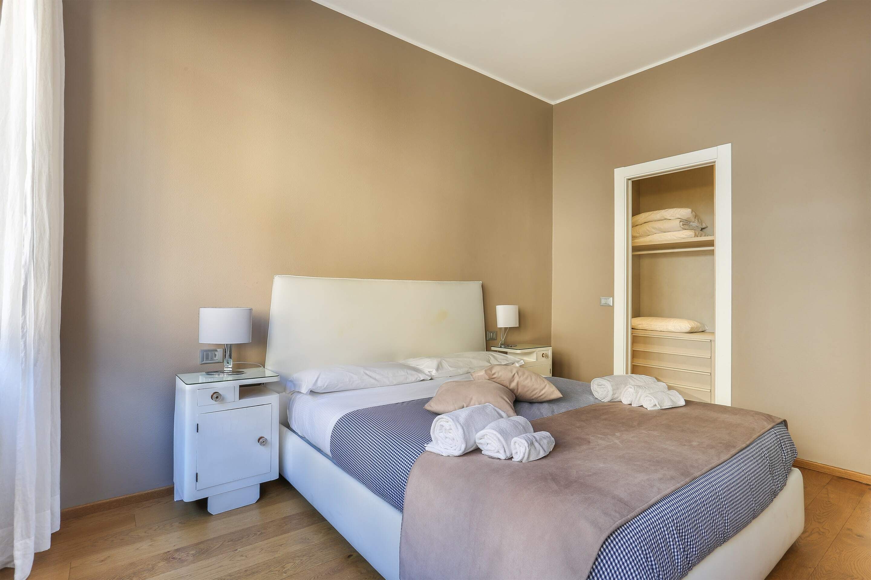A neatly arranged bedroom with a bed, bedside tables, and a wardrobe.