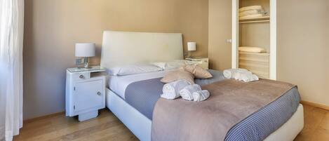 A neatly arranged bedroom with a bed, bedside tables, and a wardrobe.