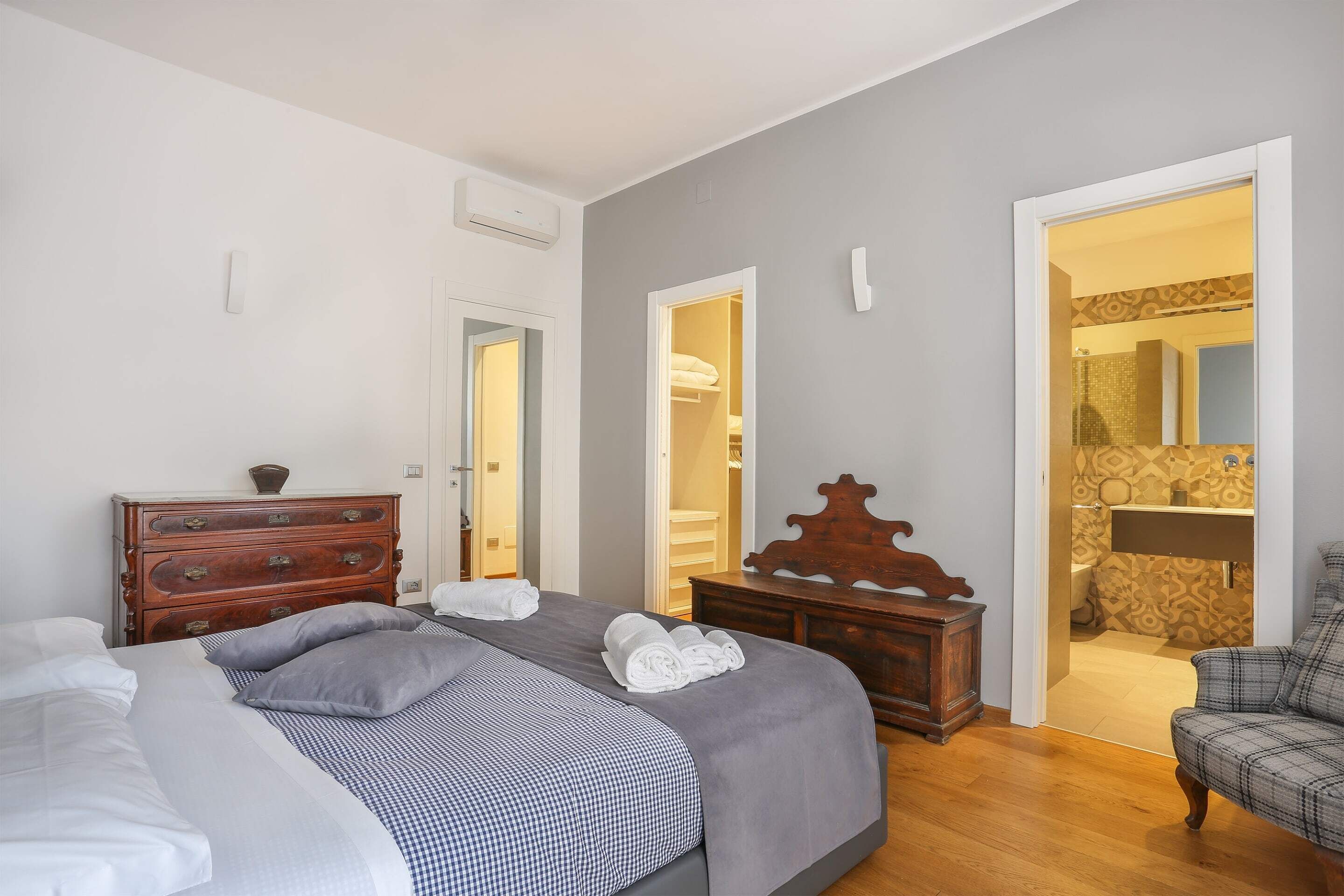 Une chambre à coucher avec un lit, une commode et une vue sur la salle de bain.