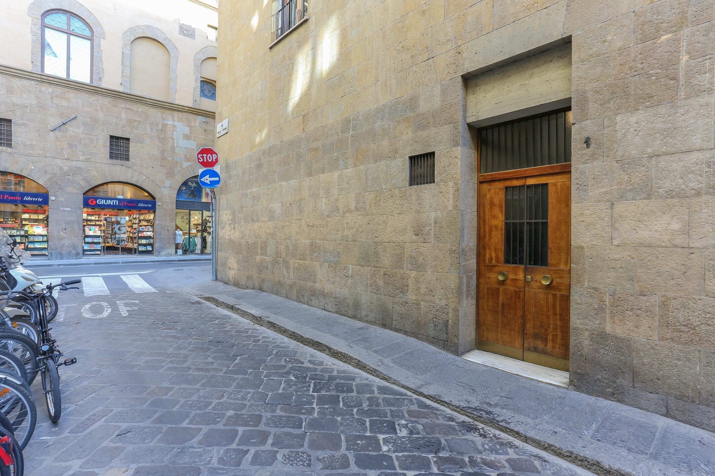 A cobblestone street with a row of parked bicycles and a closed wooden door on a stone building.