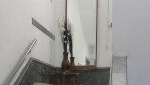 A staircase with a handrail, a mirror, and a small table with a vase. - Claridge Hotel (Montevideo)