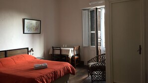A bedroom with a bed, a chair, a table, and a door. - Claridge Hotel (Montevideo)