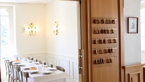 A dining area with a long table set for a meal, a wall-mounted wine rack, and a framed picture on the wall. - Hôtel Sainte Marie (Lourdes)