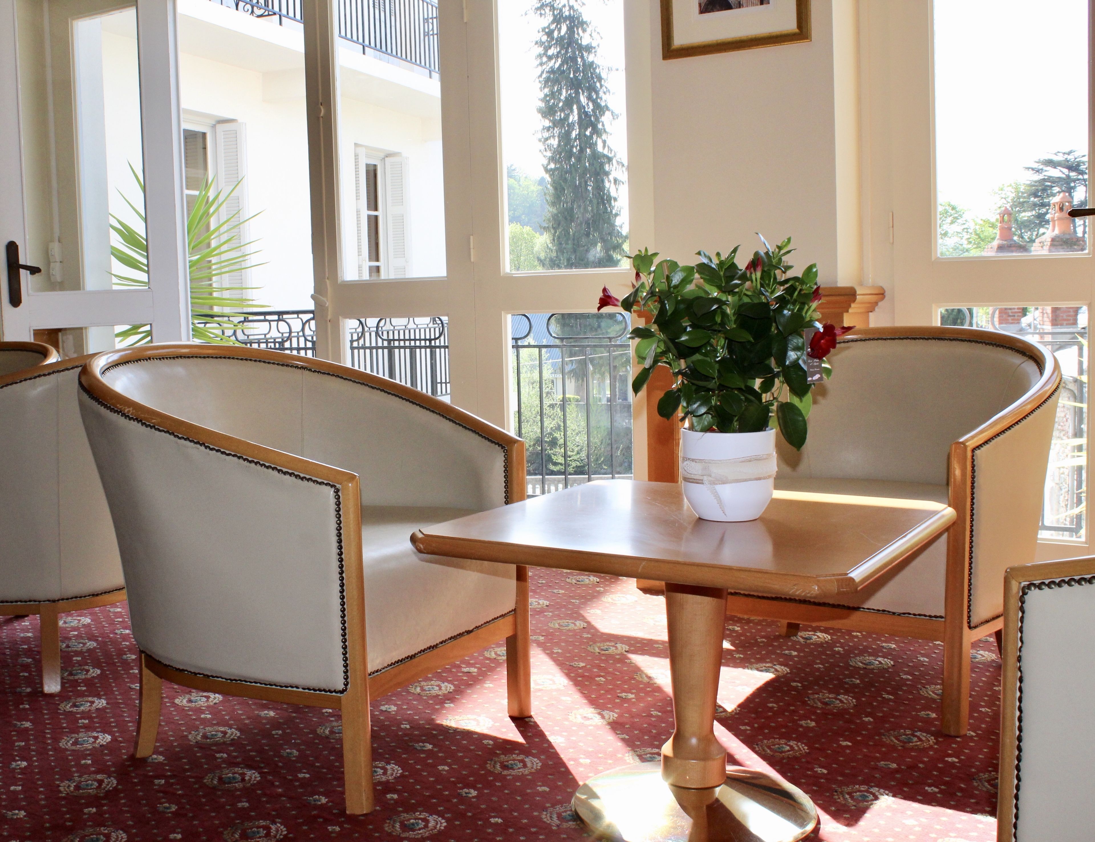 Une pièce comprenant une table et deux chaises, une plante en pot posée sur la table, et donnant sur un balcon avec une balustrade.