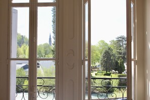 A view through a window with a balcony railing, a river, and trees in the background. - Hôtel Sainte Marie (Lourdes)