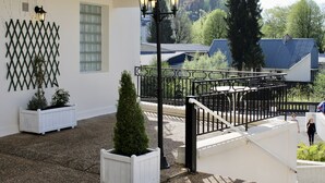 A courtyard with a white building, black railings, and potted plants. - Hôtel Sainte Marie (Lourdes)