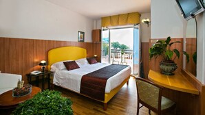 A hotel room with a bed, bedside table, chair, and a small balcony with a table and chairs. - Hotel Parco dei Principi (Grottammare)