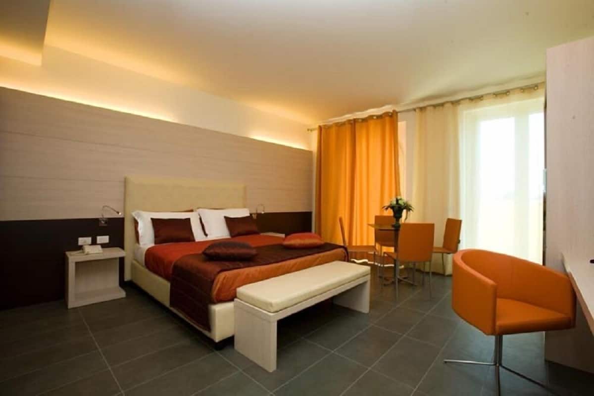 Ein modernes Hotelzimmer mit einem großen Bett, Nachttischen, einem Schreibtisch und einem Stuhl.