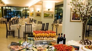 A buffet setup with seafood, fruits, and wine in a dining area with tables and chairs. - Hotel Parco dei Principi (Grottammare)
