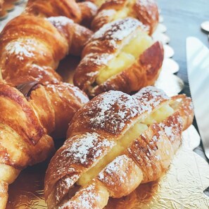 A close-up of pastries, likely croissants, with powdered sugar on top. - Hotel Villa Joseph (Mondolfo)
