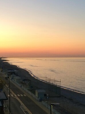 A coastal road with a beach on one side, a fence, and a few buildings. - Hotel Villa Joseph (Mondolfo)