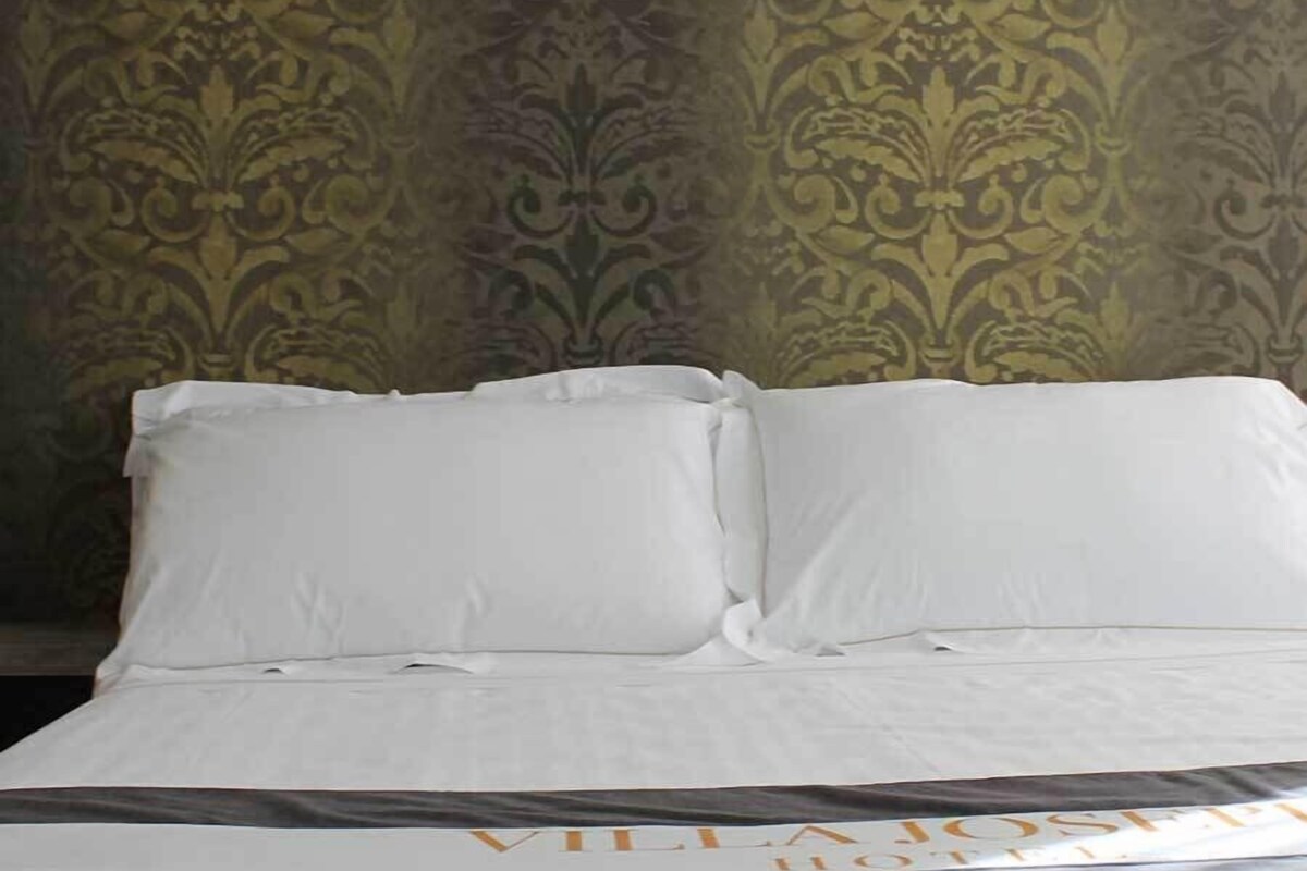 Una cama bien hecha con sábanas blancas y una colcha marrón oscuro.