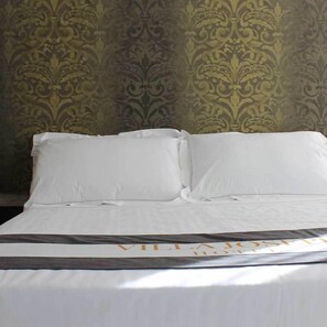 A neatly made bed with white linens and a dark brown bedspread. - Hotel Villa Joseph (Mondolfo)