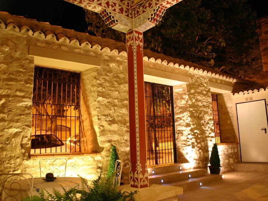 A stone building with barred windows and a door, illuminated by warm lighting.