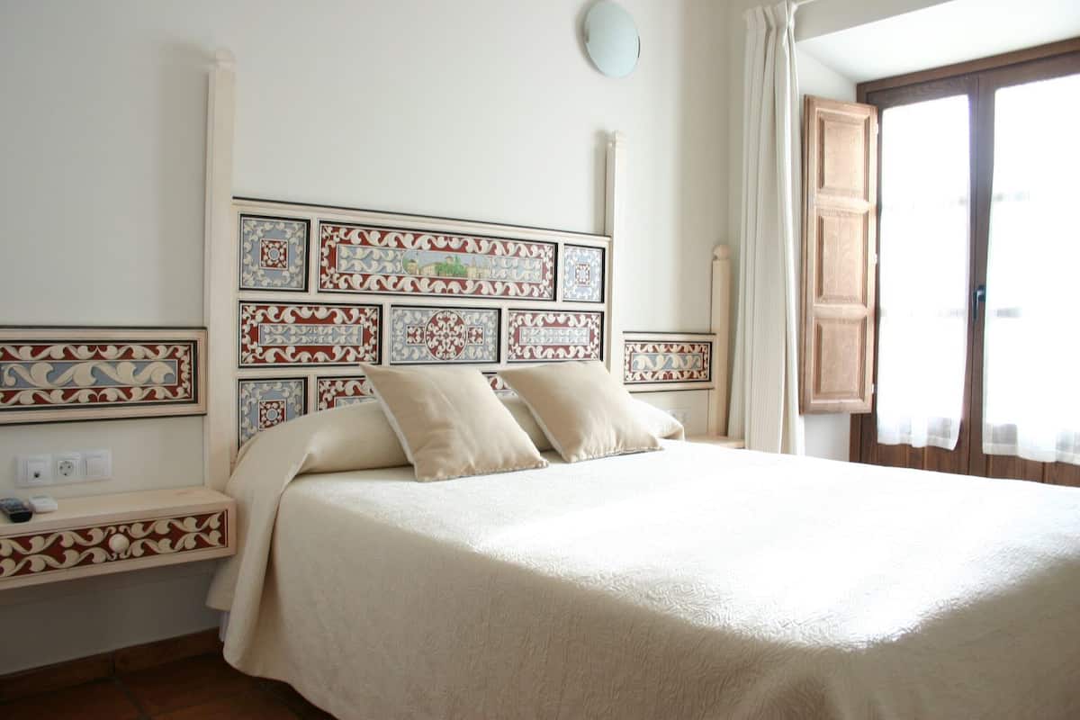 A bedroom with a large bed, a bedside table, a mirror, and patterned wall decorations.