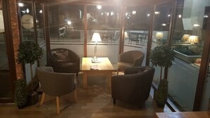 Un coin salon confortable avec une table et des chaises, une lampe et une vue à travers un mur de verre.