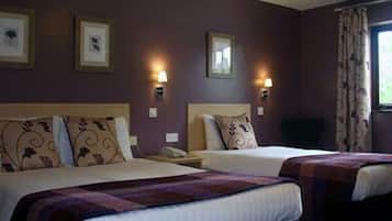 Een hotelkamer met twee bedden, een raam met gordijnen en wandlampen.