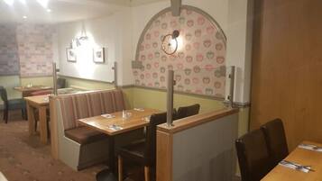 Restaurante com boxes e mesas, parede de tijolos e parede decorada com corações.