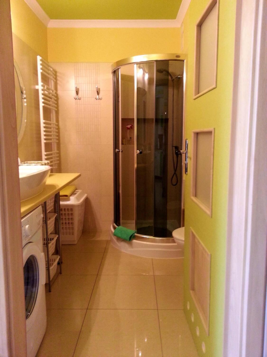 A compact bathroom with a shower, a washing machine, and a toilet.