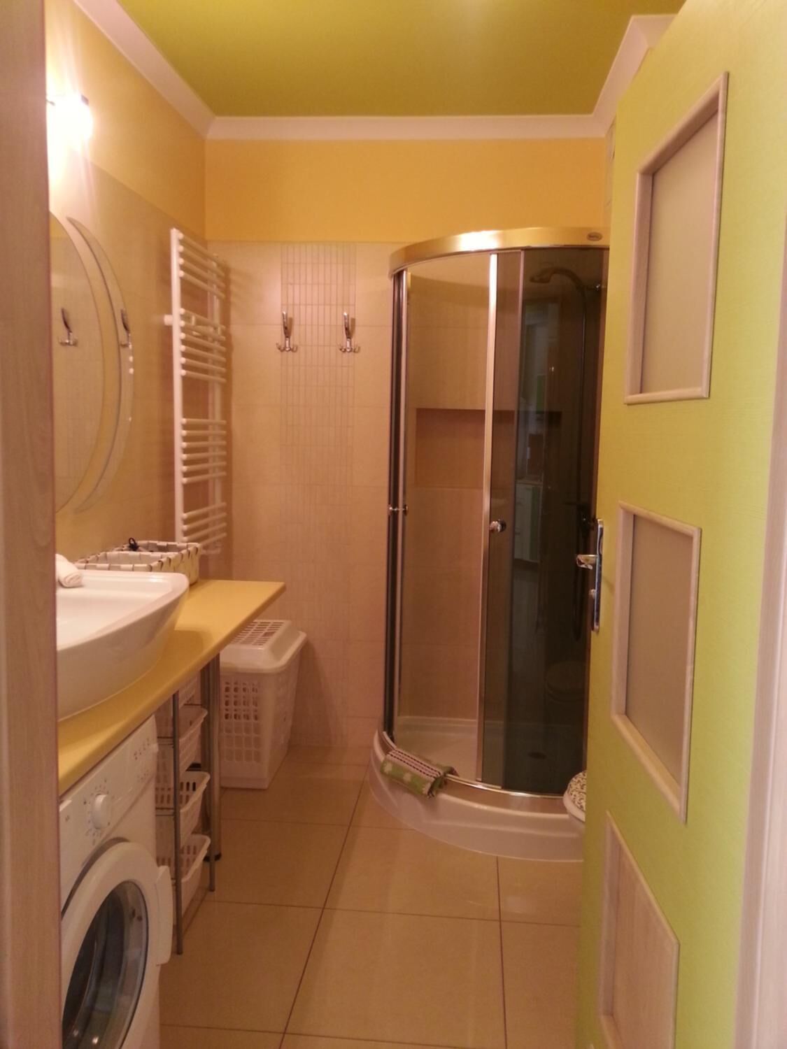 A compact bathroom with a shower, a sink, and a washing machine.