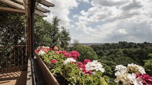 Varanda com pérgola de madeira e vista para uma paisagem verdejante, com uma cidade ao longe.
