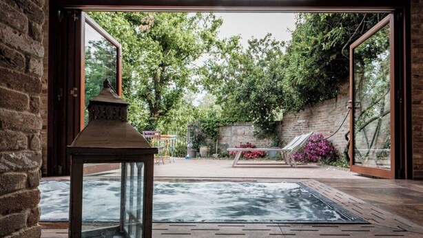 Uma área de spa com hidromassagem, um compartimento de vidro e uma parede de tijolos.