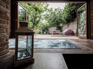 Un área de spa con una bañera de hidromasaje, un recinto de vidrio y una pared de ladrillo.