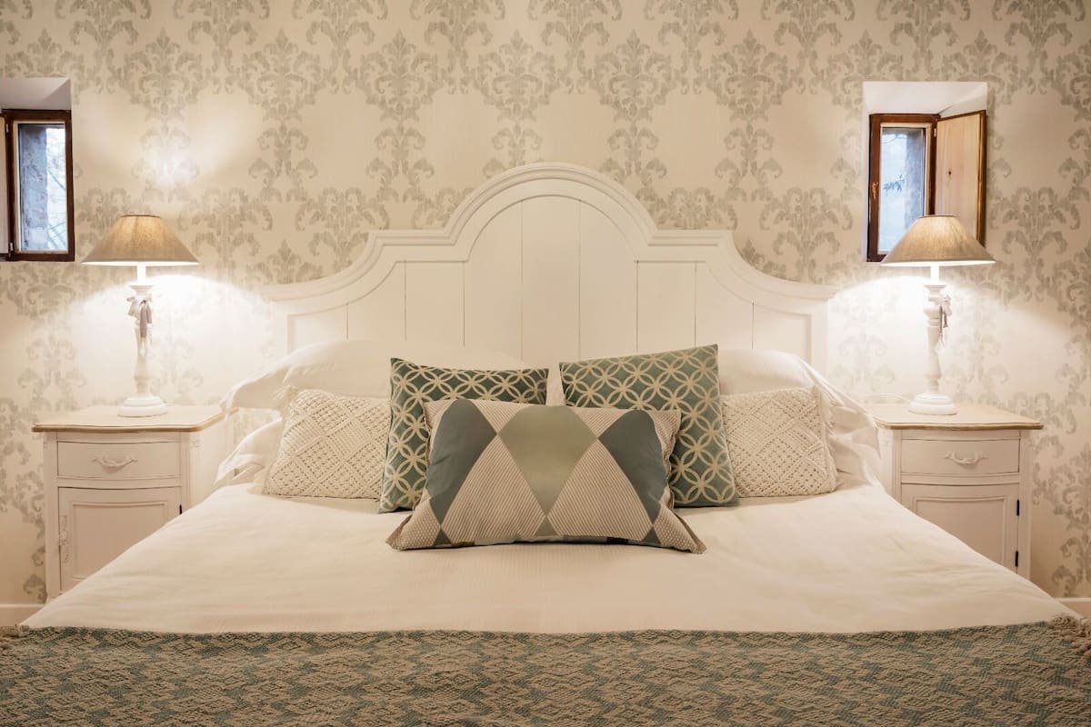 A bedroom with a large bed, two bedside tables, and a headboard.