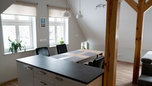 A modern kitchen with a central island, wooden beams, and large windows. - Apartamenty Marina (Ustka)