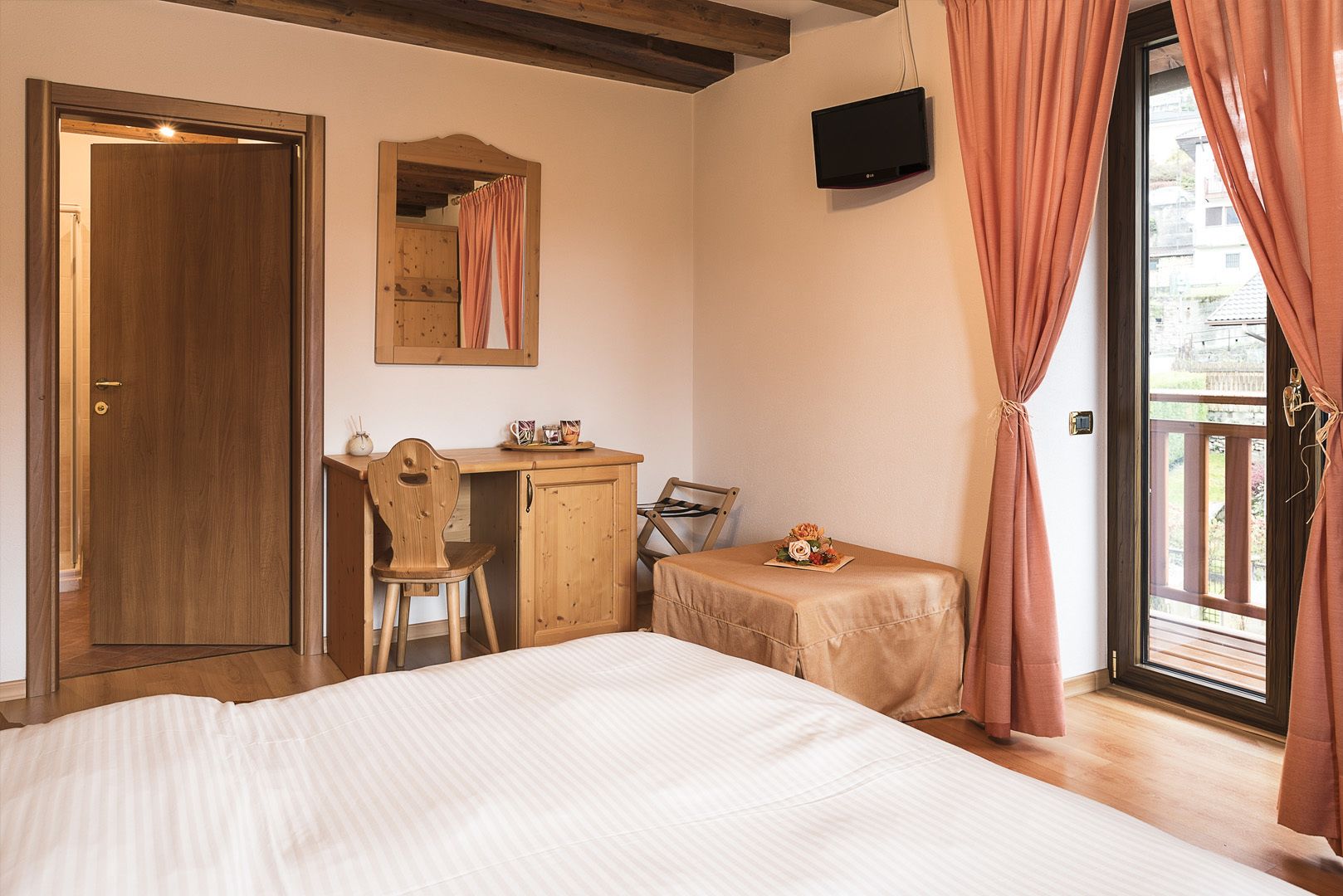 Una camera da letto con un letto, una scrivania in legno, una sedia e un tavolino con un vaso di fiori.