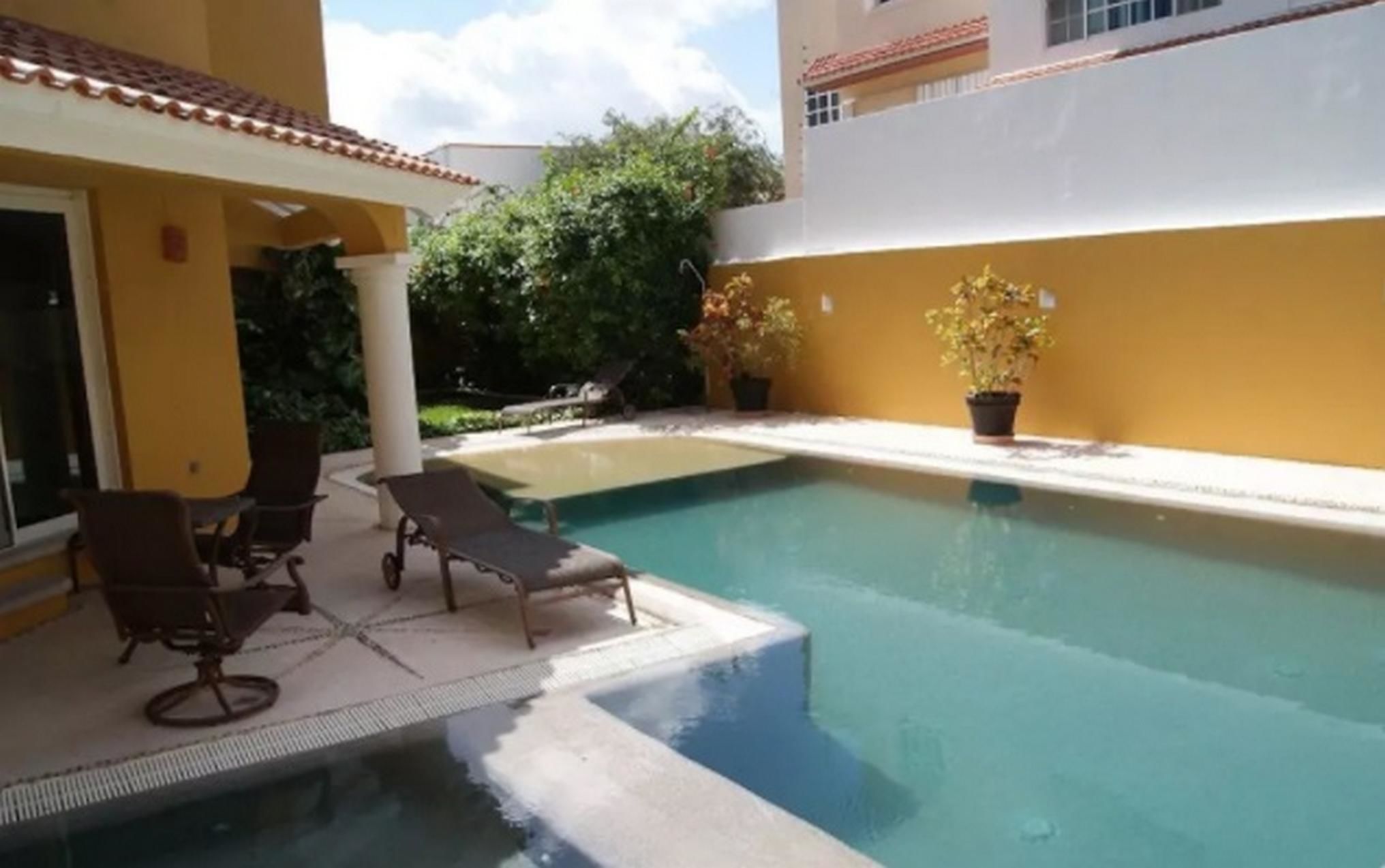Piscina com espreguiçadeiras e plantas em vasos.