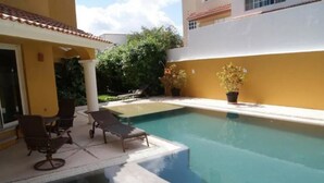 Une piscine avec des chaises longues et des plantes en pot.