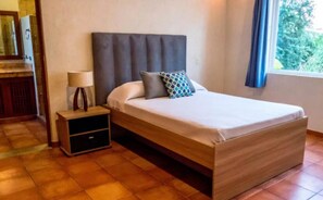 Une chambre à coucher avec un lit, une table de chevet et une fenêtre avec des rideaux.