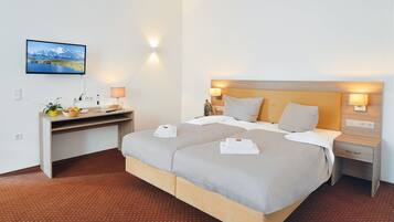 Een hotelkamer met een groot bed, een bureau met een computer en een aan de muur bevestigde televisie.