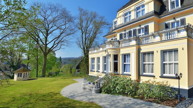 Ein großes, zweistöckiges Haus mit gepflegtem Rasen und einem Weg zum Eingang.